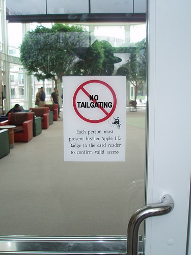 A "no tailgating" sign at Apple's corporate office — a representative awareness-control deployment. The sign-based defense layer is the cheapest physical-entry deterrent: it costs essentially nothi…